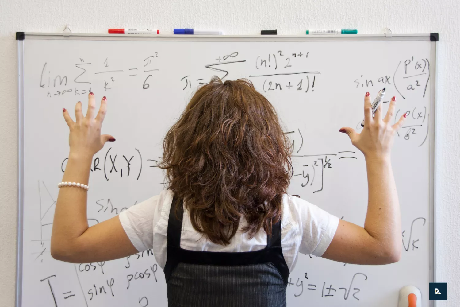 Teenager von hinten an einem Whiteboard mit Matheaufgabe stehend